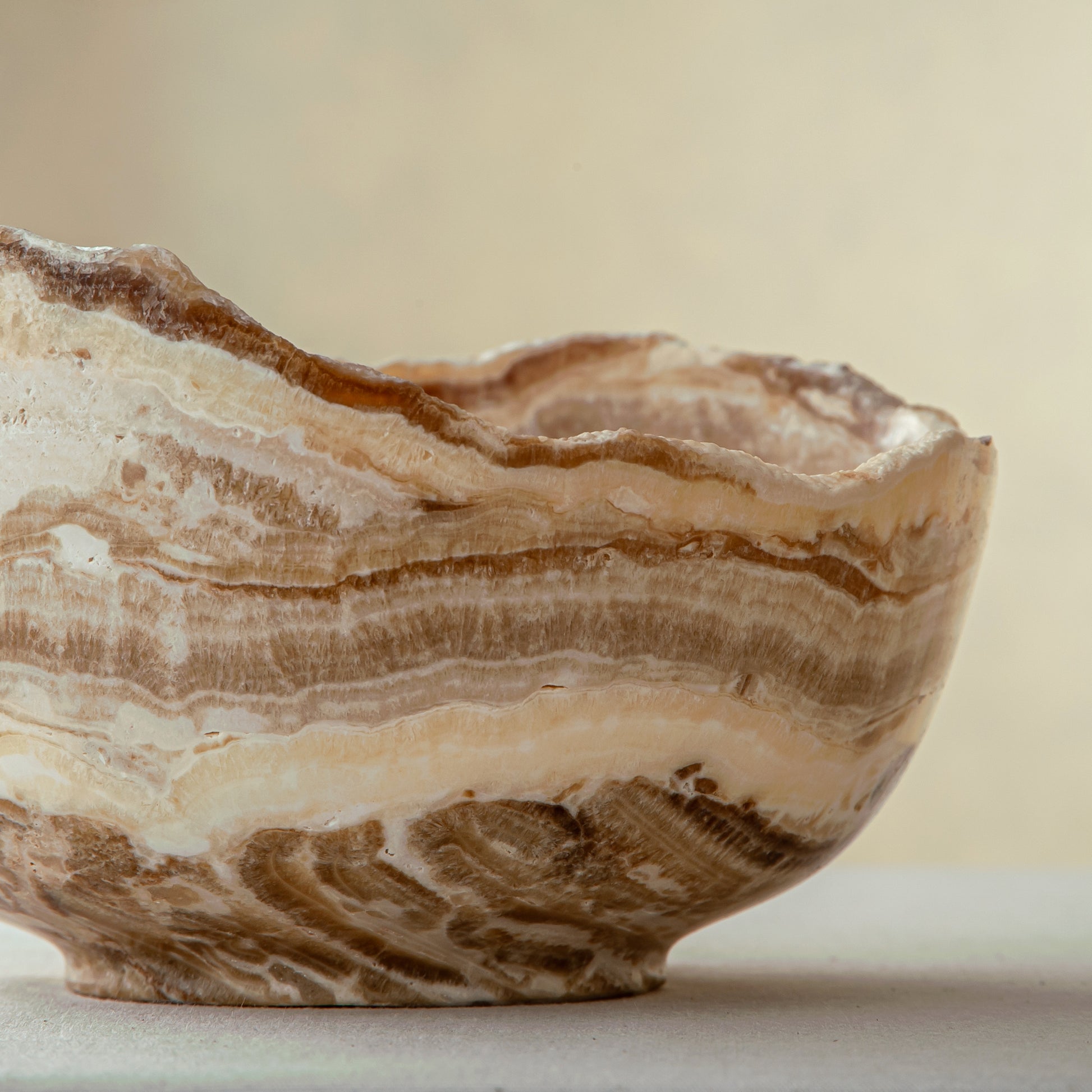 handcrafted stone bowl in onyx with textured edge and rich banding for coffee table styling