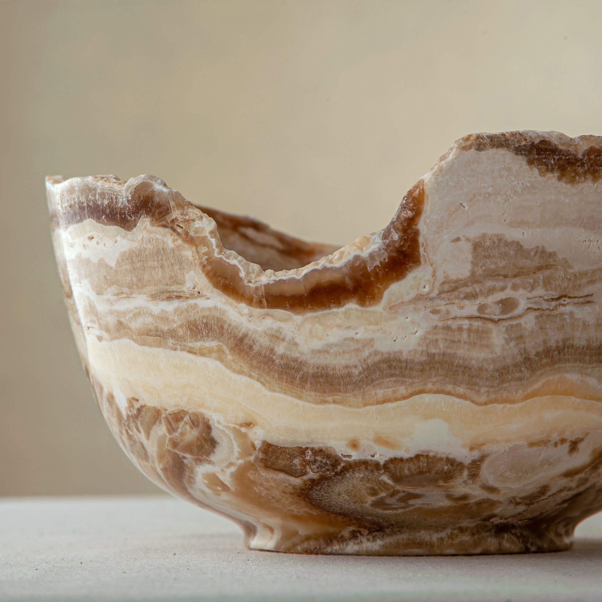 handcrafted stone bowl in onyx with textured edge and rich banding for coffee table styling