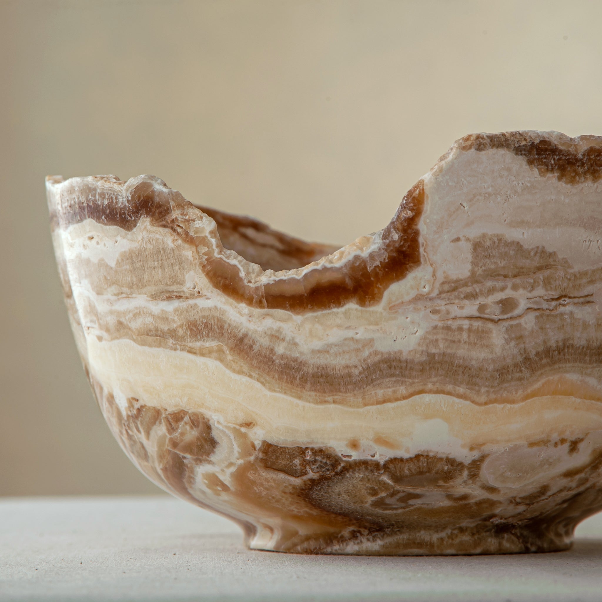 handcrafted stone bowl in onyx with textured edge and rich banding for coffee table styling