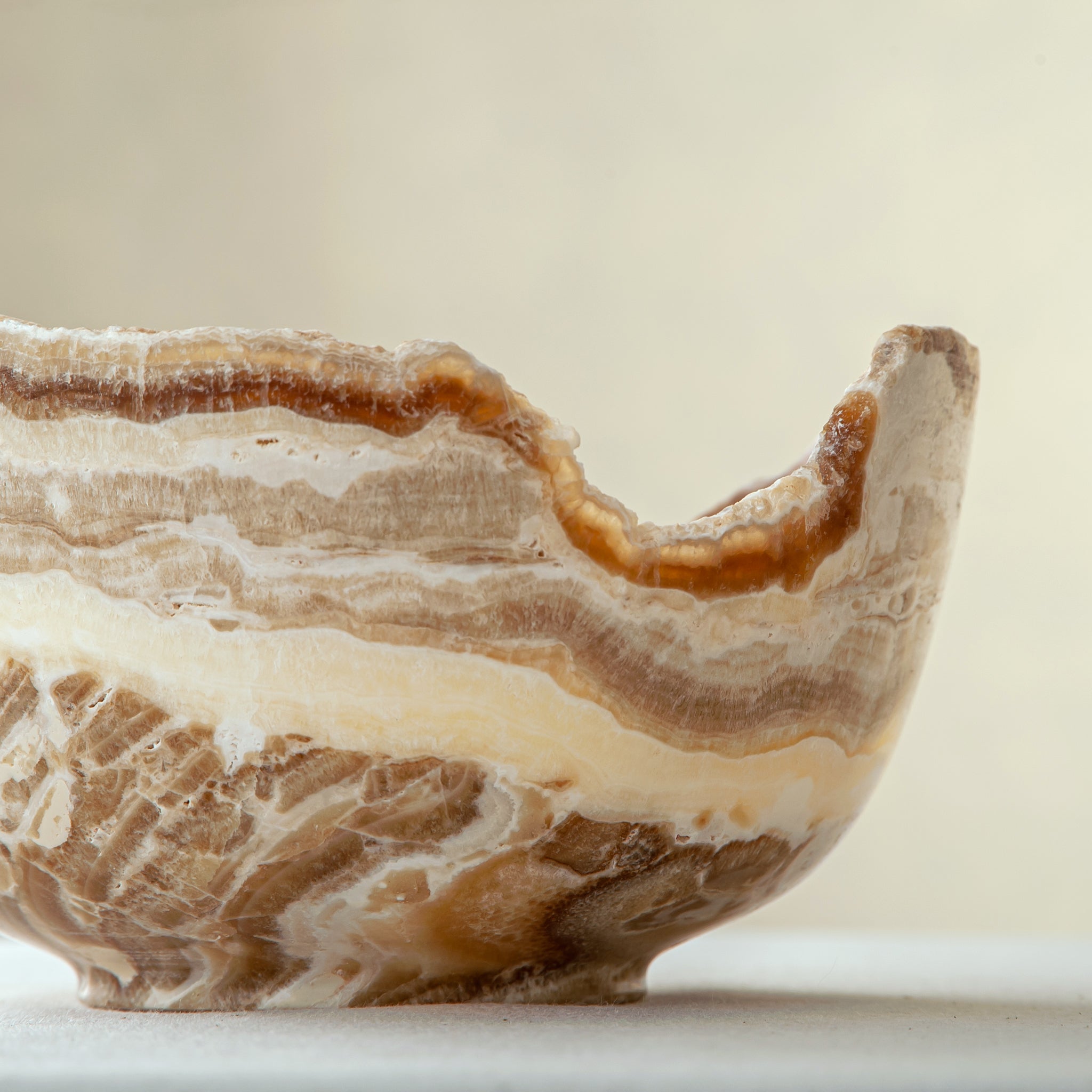 handcrafted stone bowl in onyx with textured edge and rich banding for coffee table styling