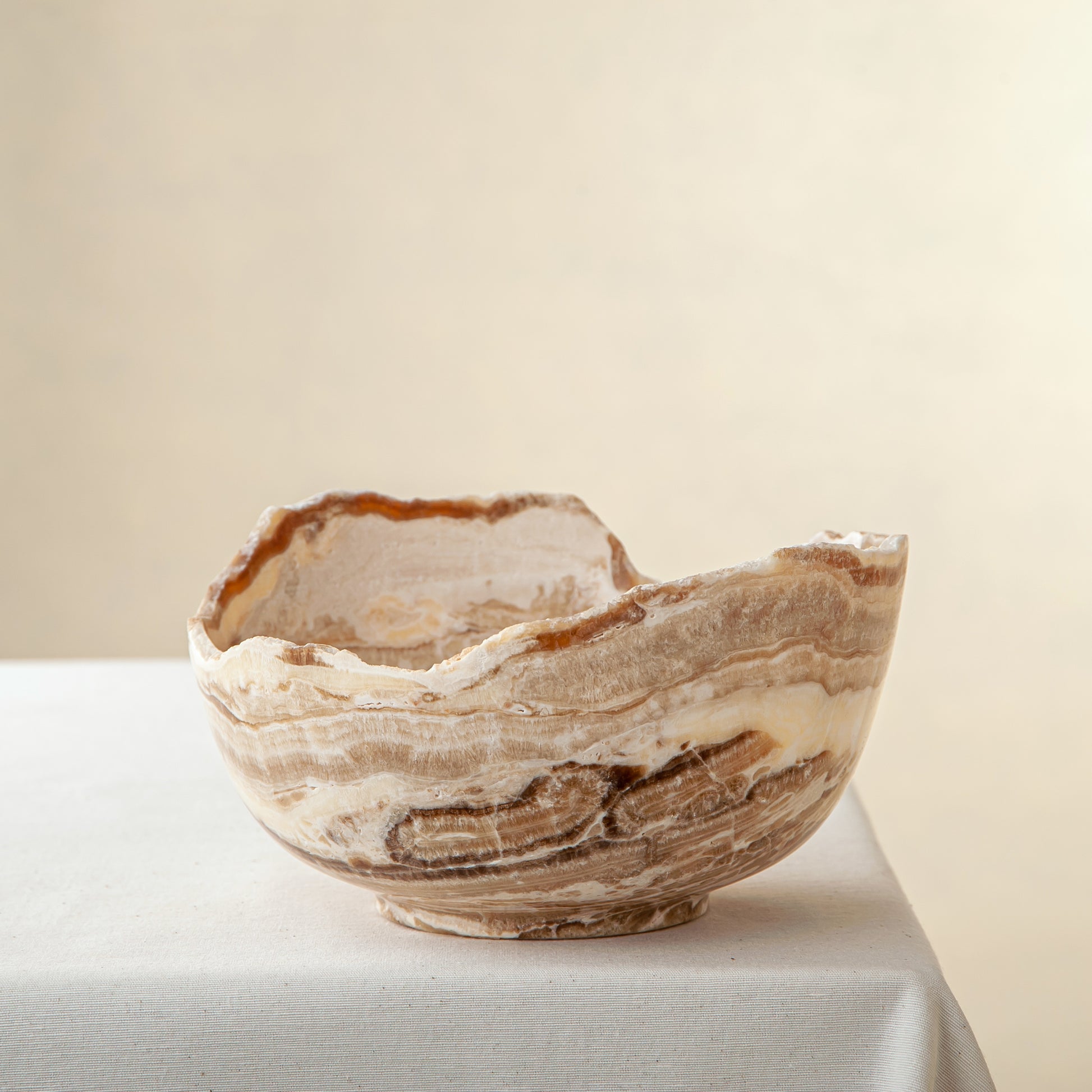 handcrafted stone bowl in onyx with textured edge and rich banding for coffee table styling