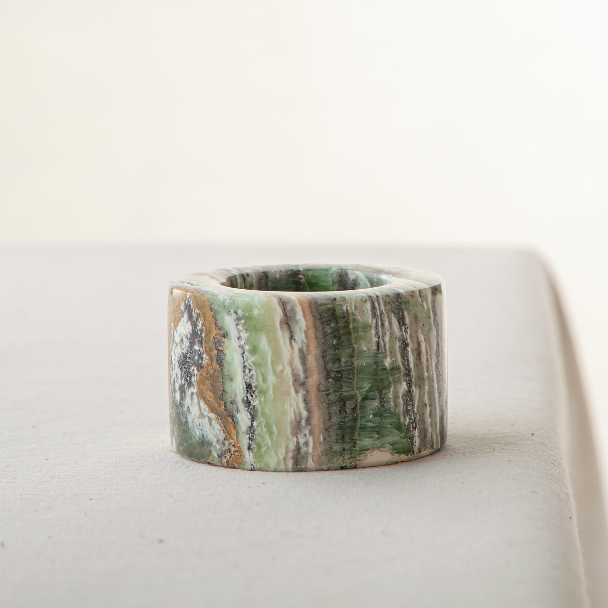 Handcrafted green onyx candle holder with natural banding and cylindrical sculptural form
