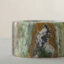 Handcrafted green onyx candle holder with natural banding and cylindrical sculptural form
