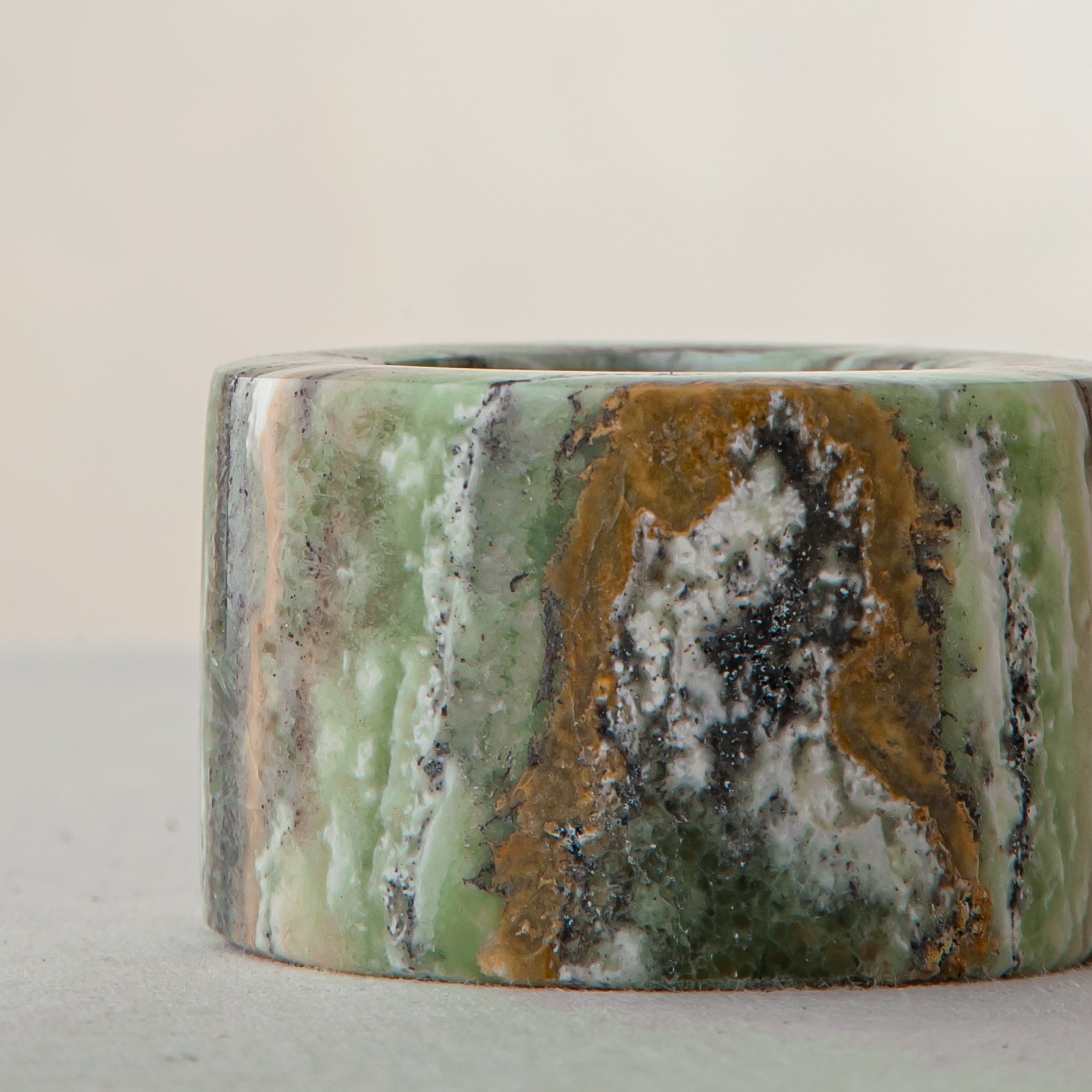 Handcrafted green onyx candle holder with natural banding and cylindrical sculptural form
