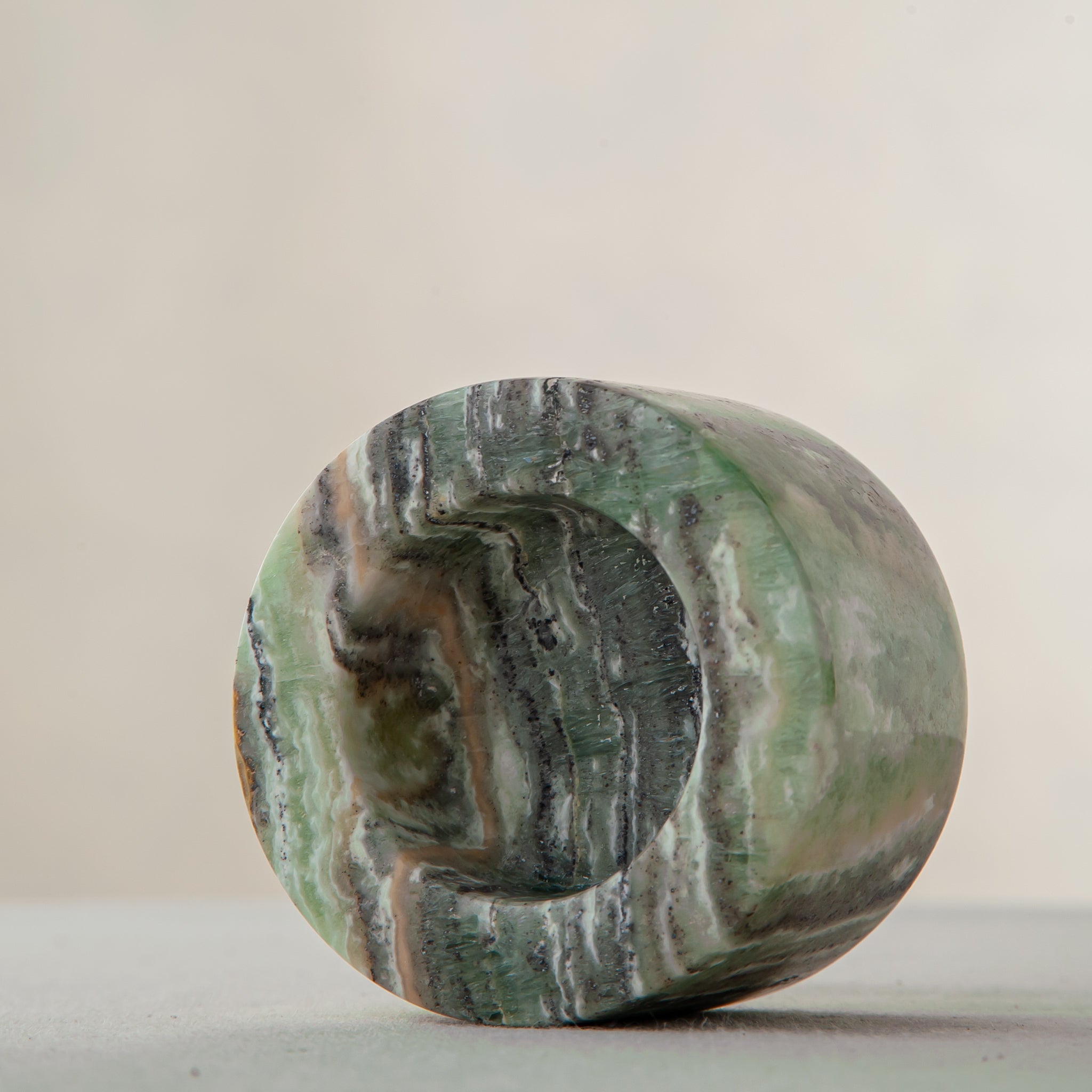 Handcrafted green onyx candle holder with natural banding and cylindrical sculptural form
