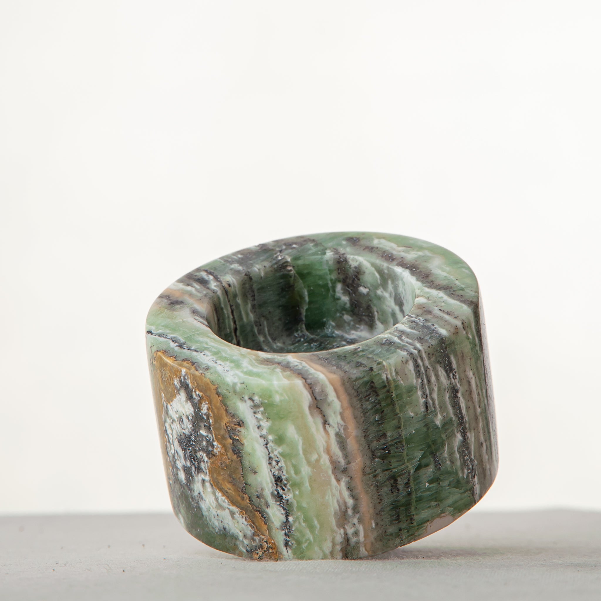 Handcrafted green onyx candle holder with natural banding and cylindrical sculptural form
