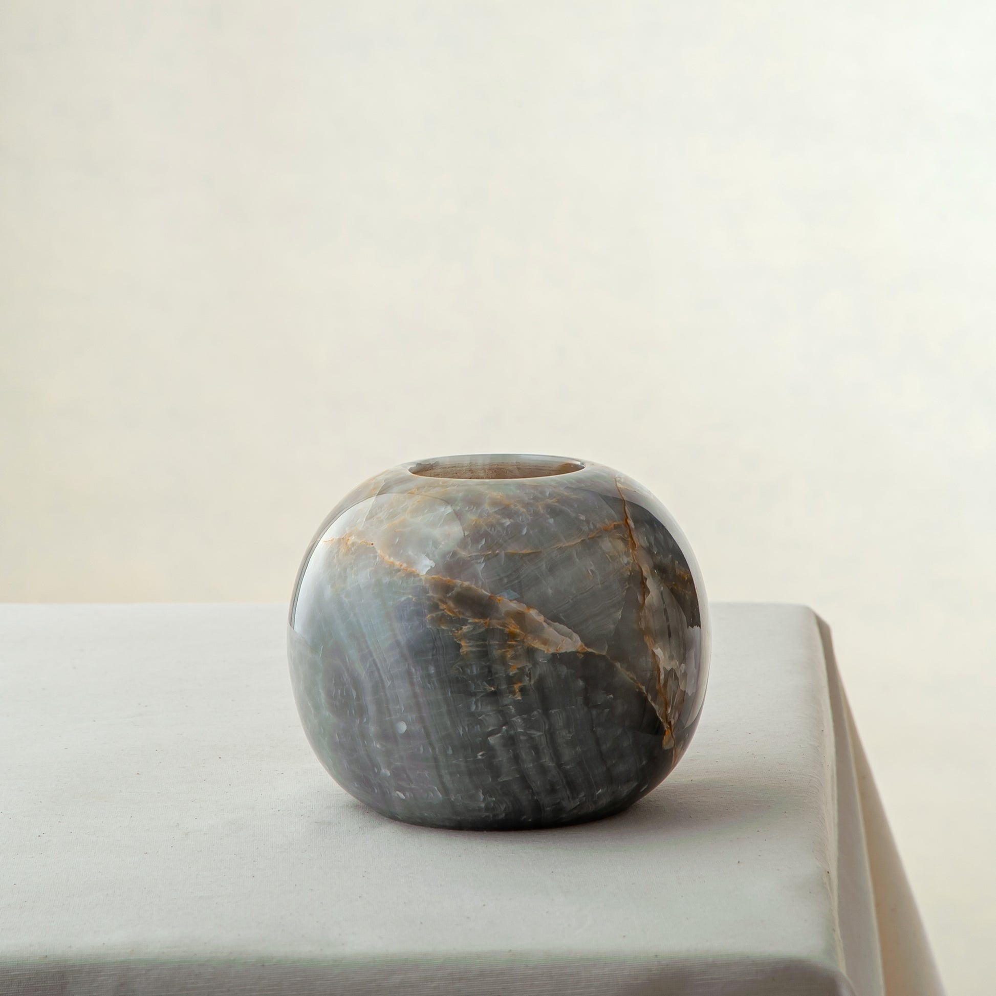 handcrafted onyx candle holder with rounded shape and dark grey amber veining
