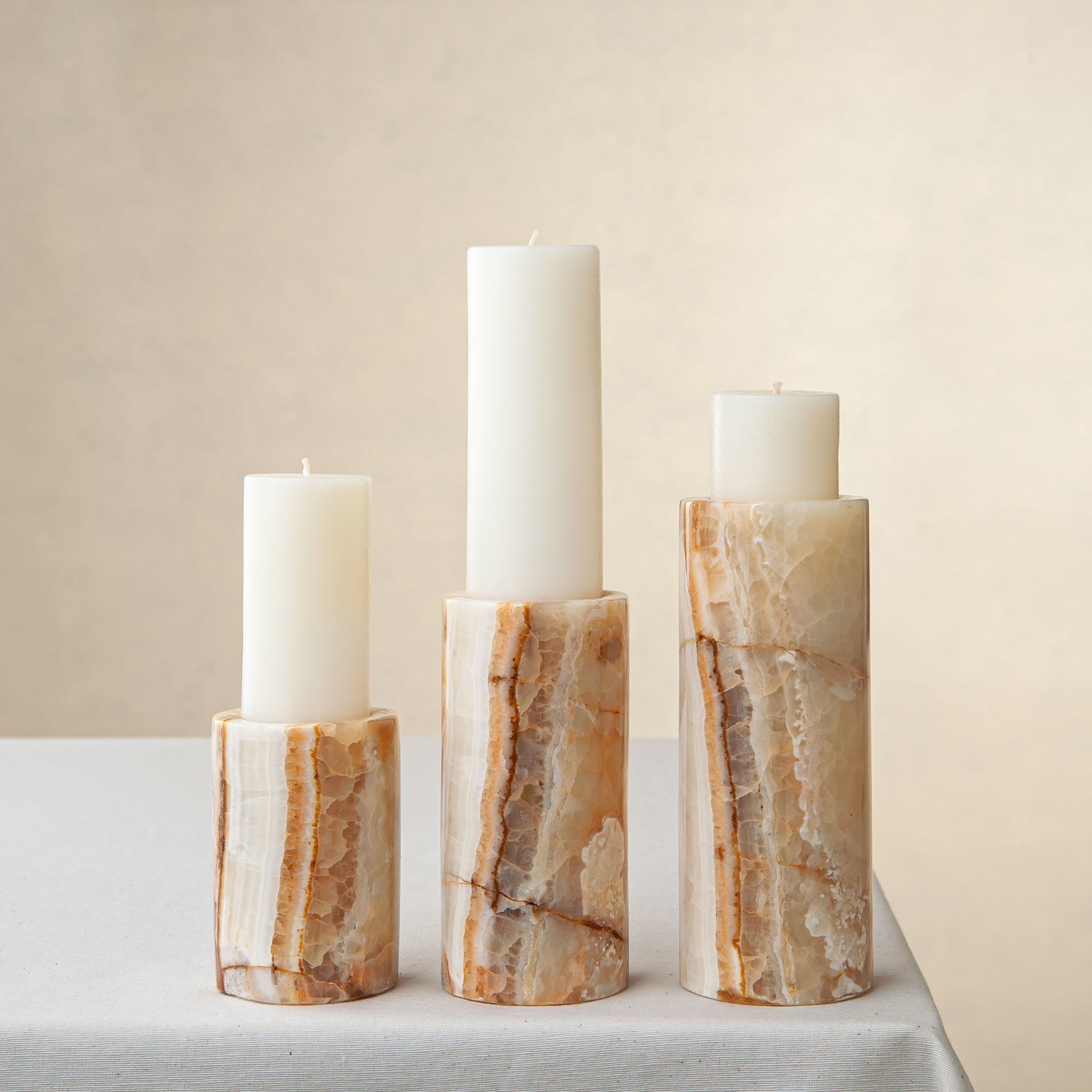 Unique onyx candle holder set with amber veining and cylindrical sculptural forms

