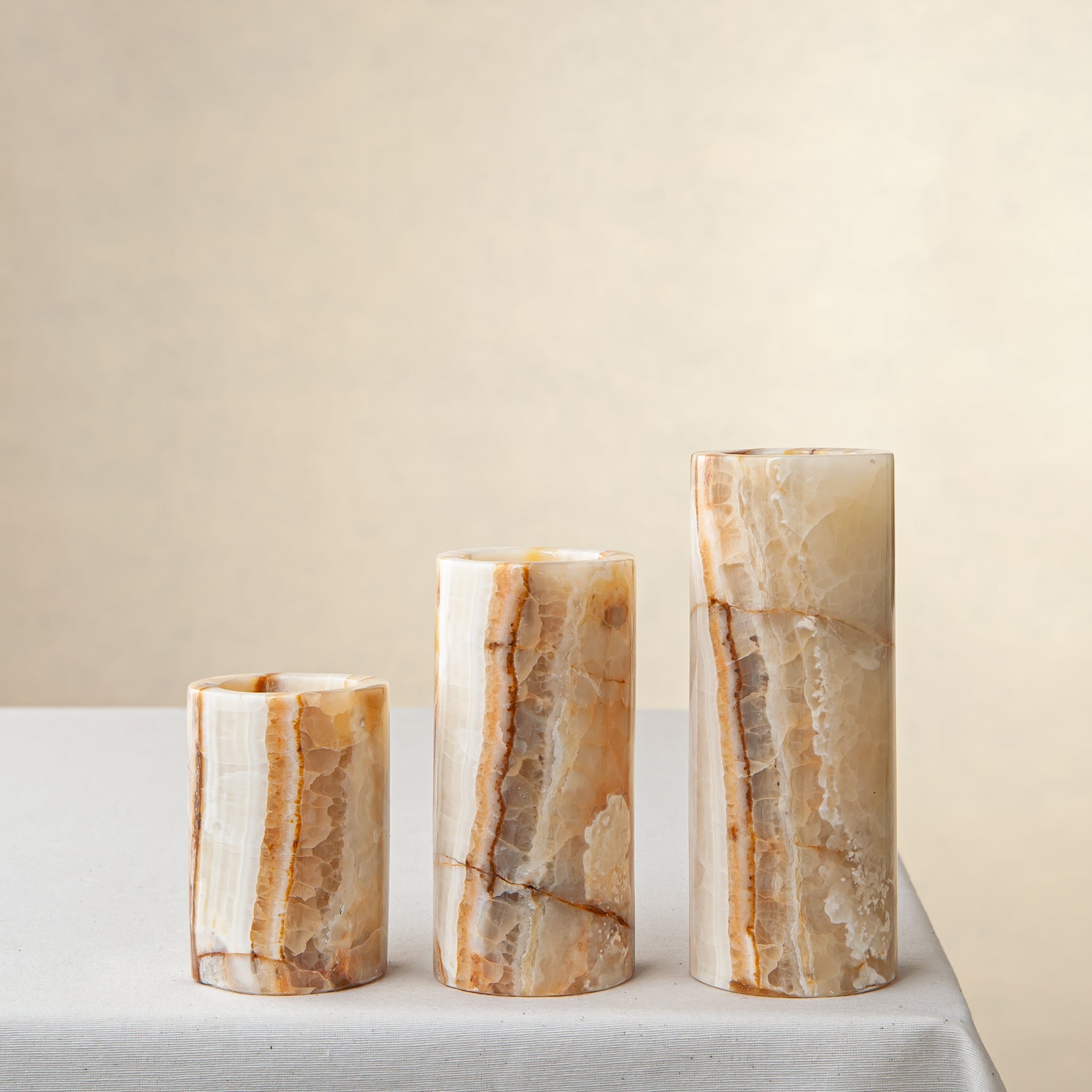 Unique onyx candle holder set with amber veining and cylindrical sculptural forms
