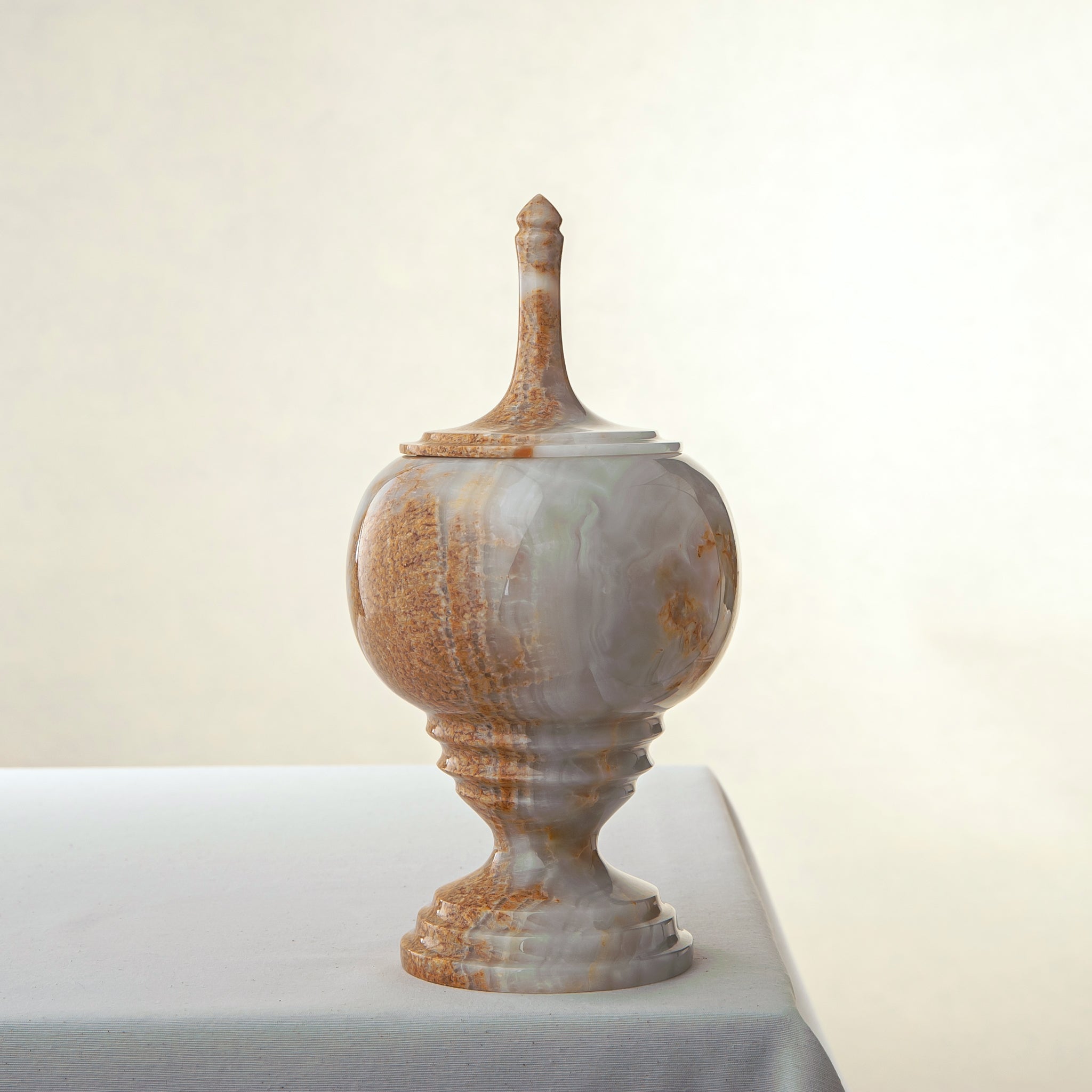 Handcrafted onyx jar with lid in translucent ivory and rust veining as sculptural centerpiece
