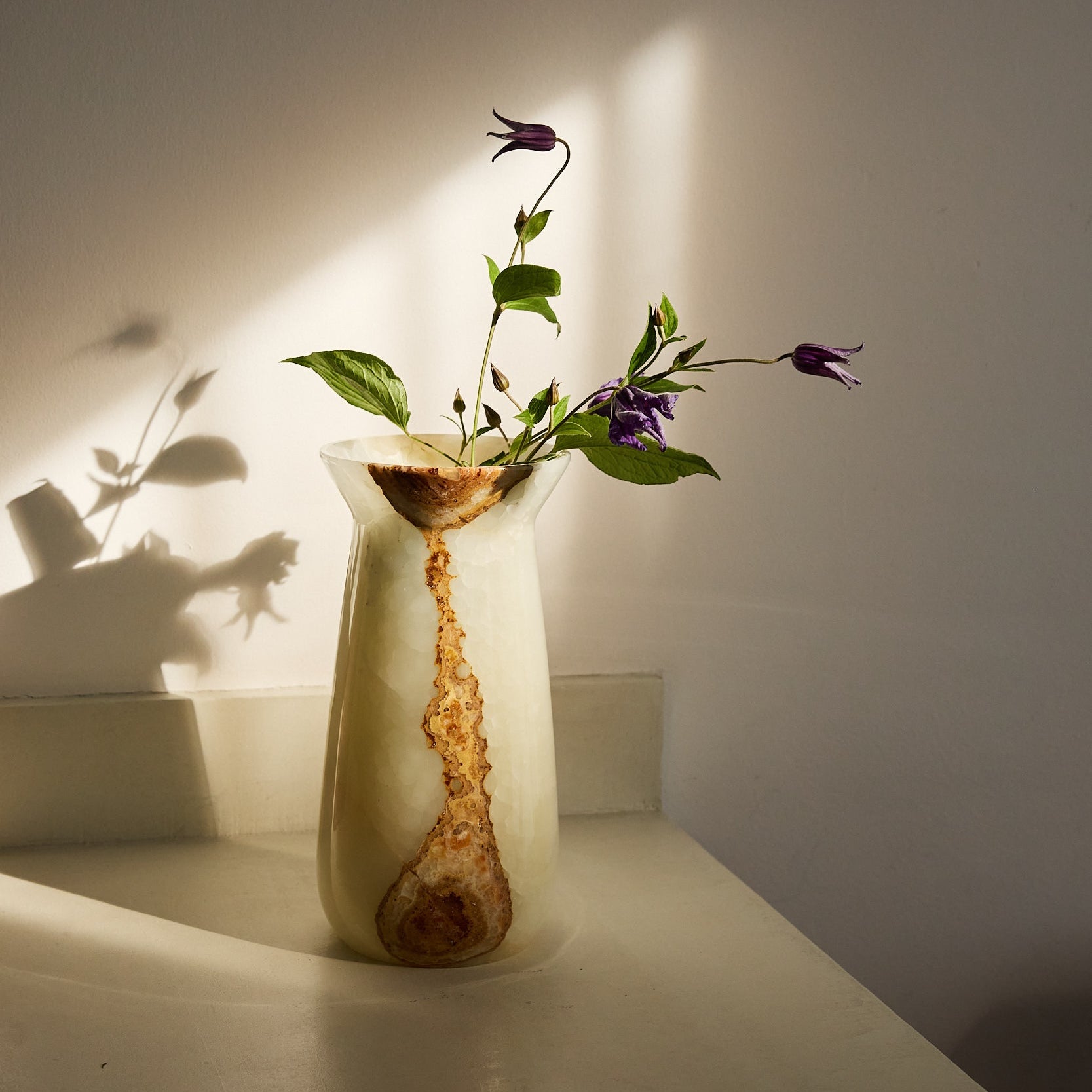 Unique onyx vase with luminous ivory stone and flowing amber mineral veining
