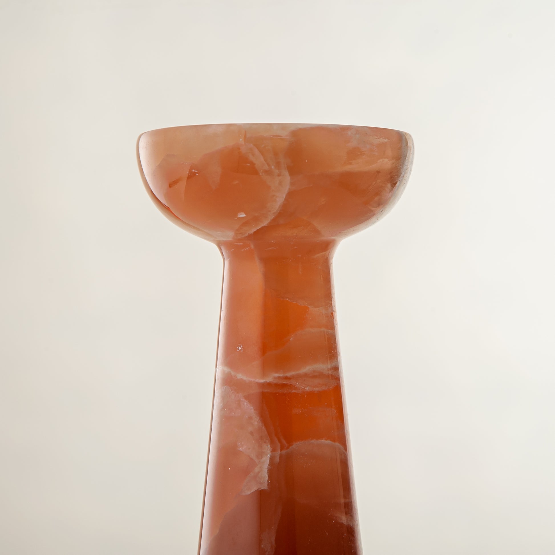 handcrafted orange onyx candle holder with tall sculptural form and translucent veining for modern decor

