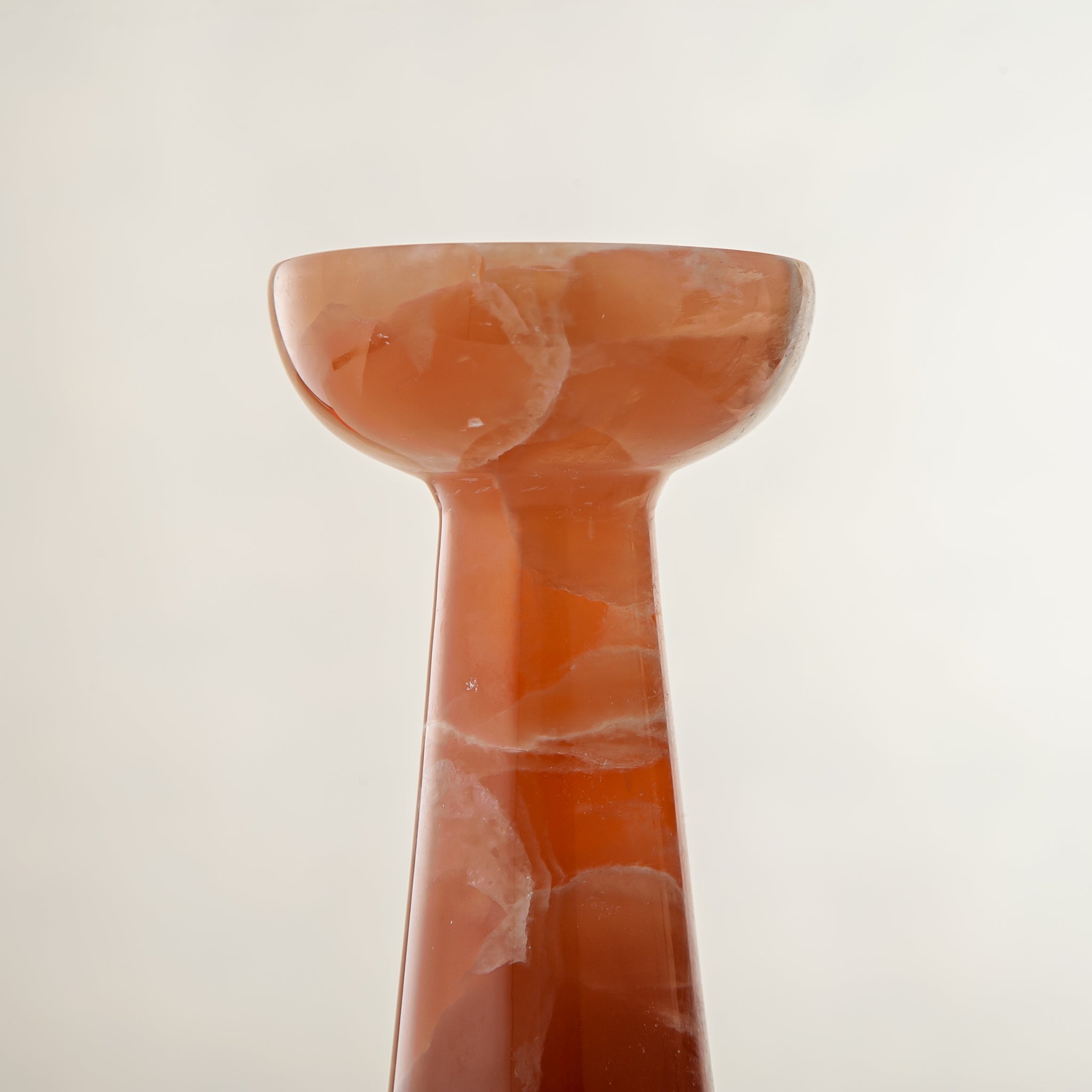 handcrafted orange onyx candle holder with tall sculptural form and translucent veining for modern decor
