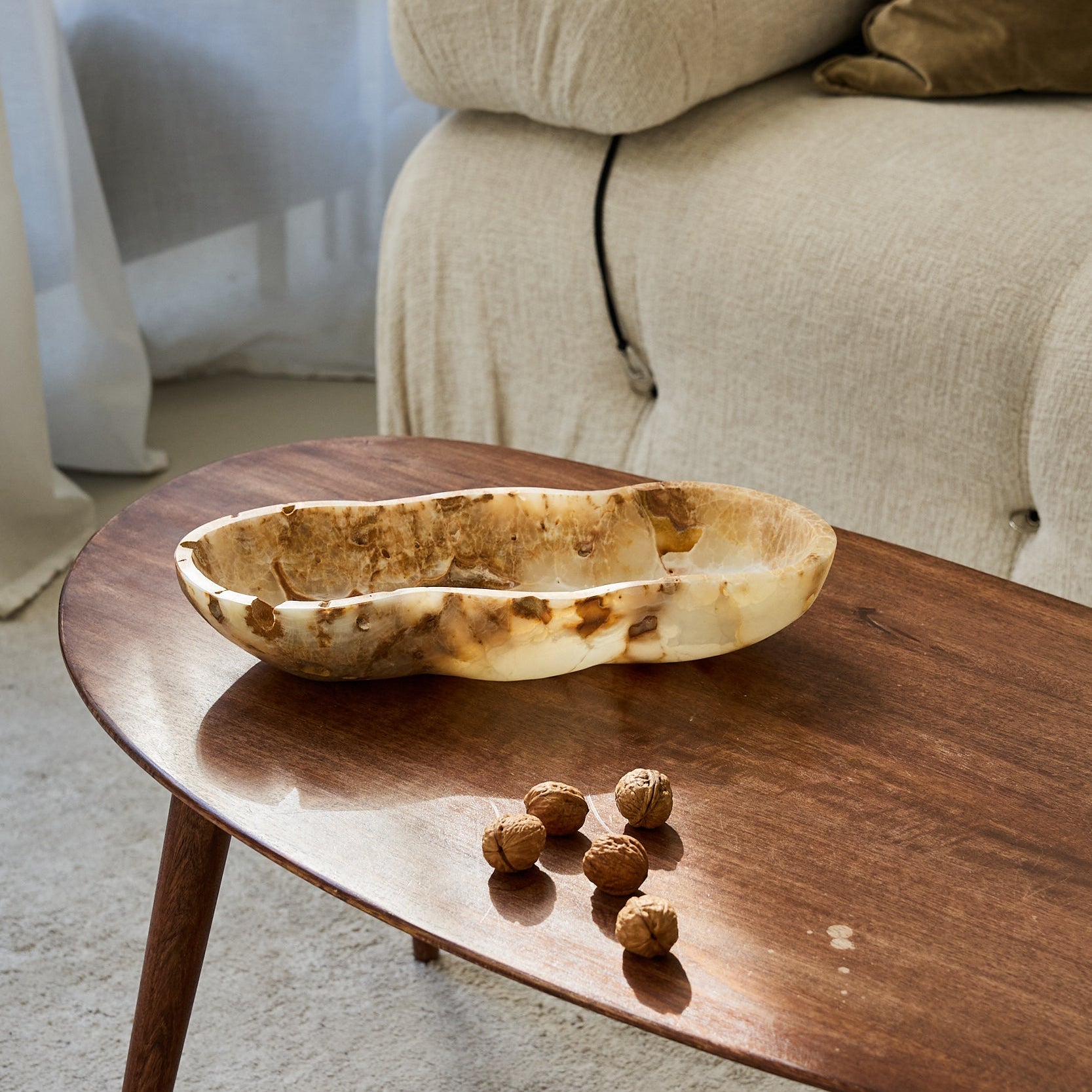 Unique rough onyx bowl with natural openings and translucent ivory stone texture

