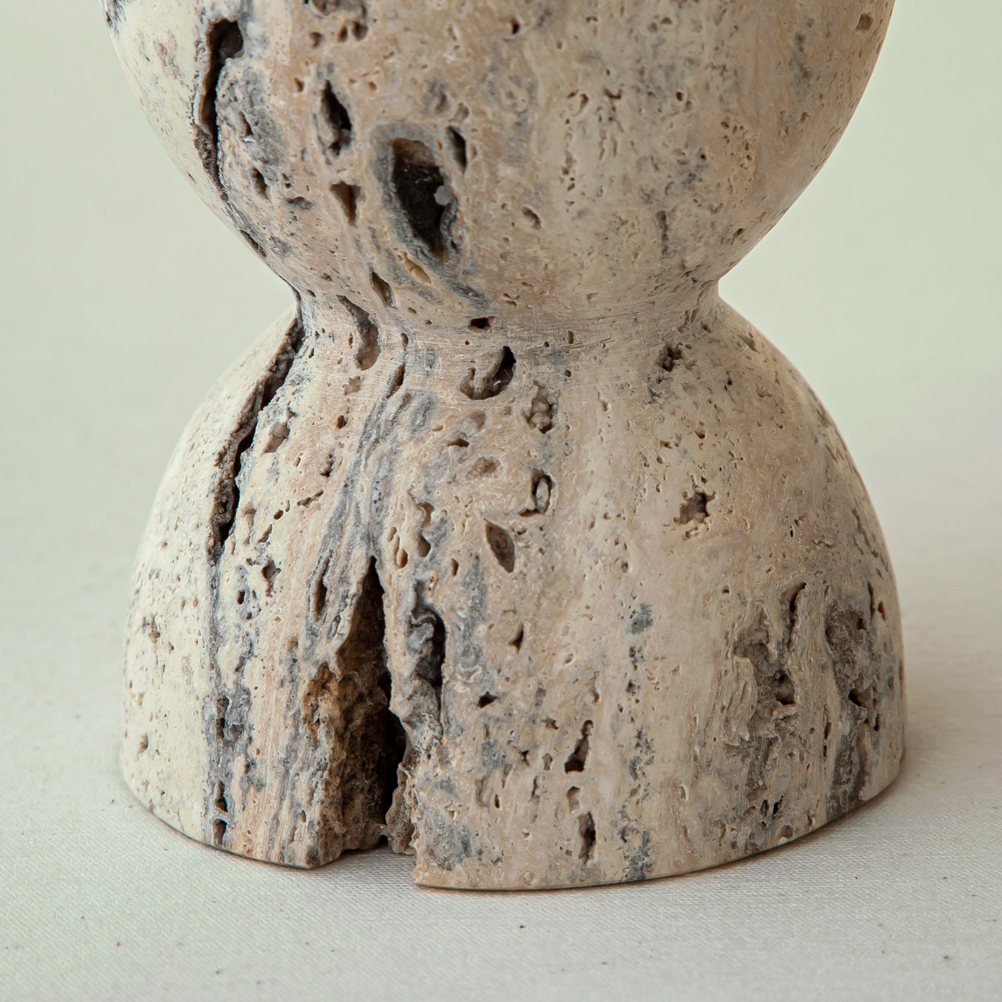 handcrafted travertine candle holder with porous texture and hourglass shape for modern decor
