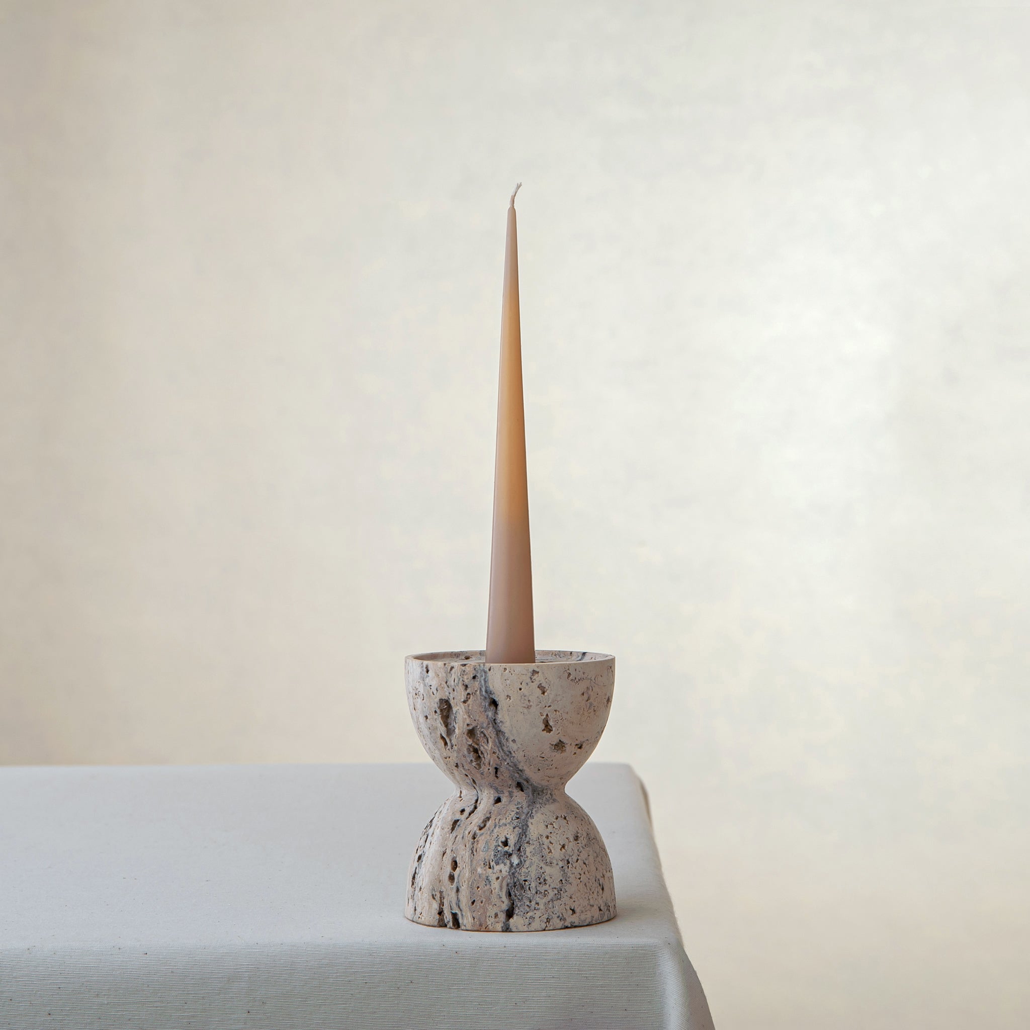 handcrafted travertine candle holder with porous texture and hourglass shape for modern decor
