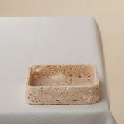 Handcrafted travertine tray with porous texture in soft beige tones as modern table decor
