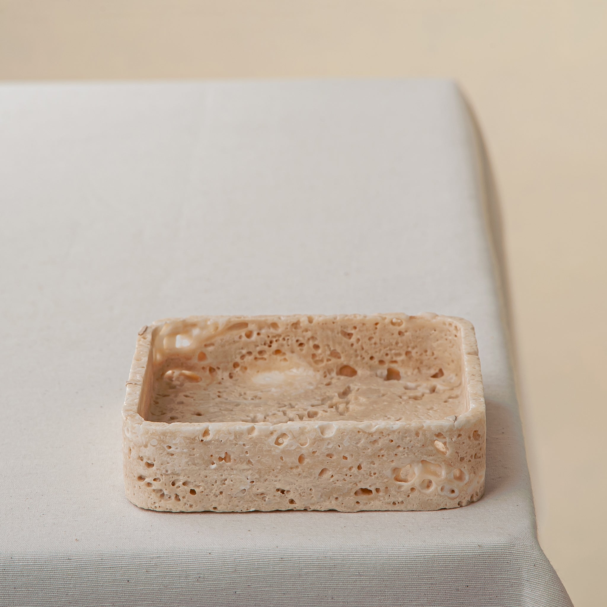 Handcrafted travertine tray with porous texture in soft beige tones as modern table decor
