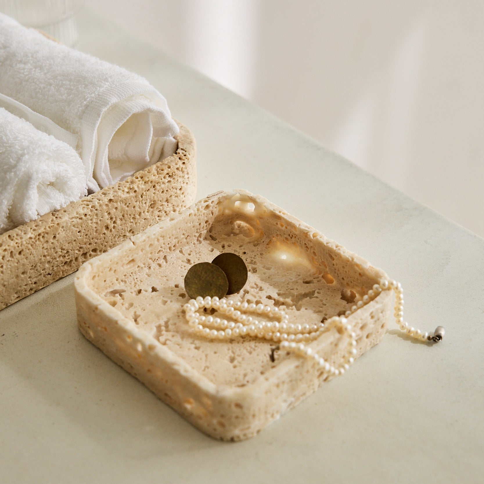 Handcrafted travertine tray with porous texture in soft beige tones as modern table decor
