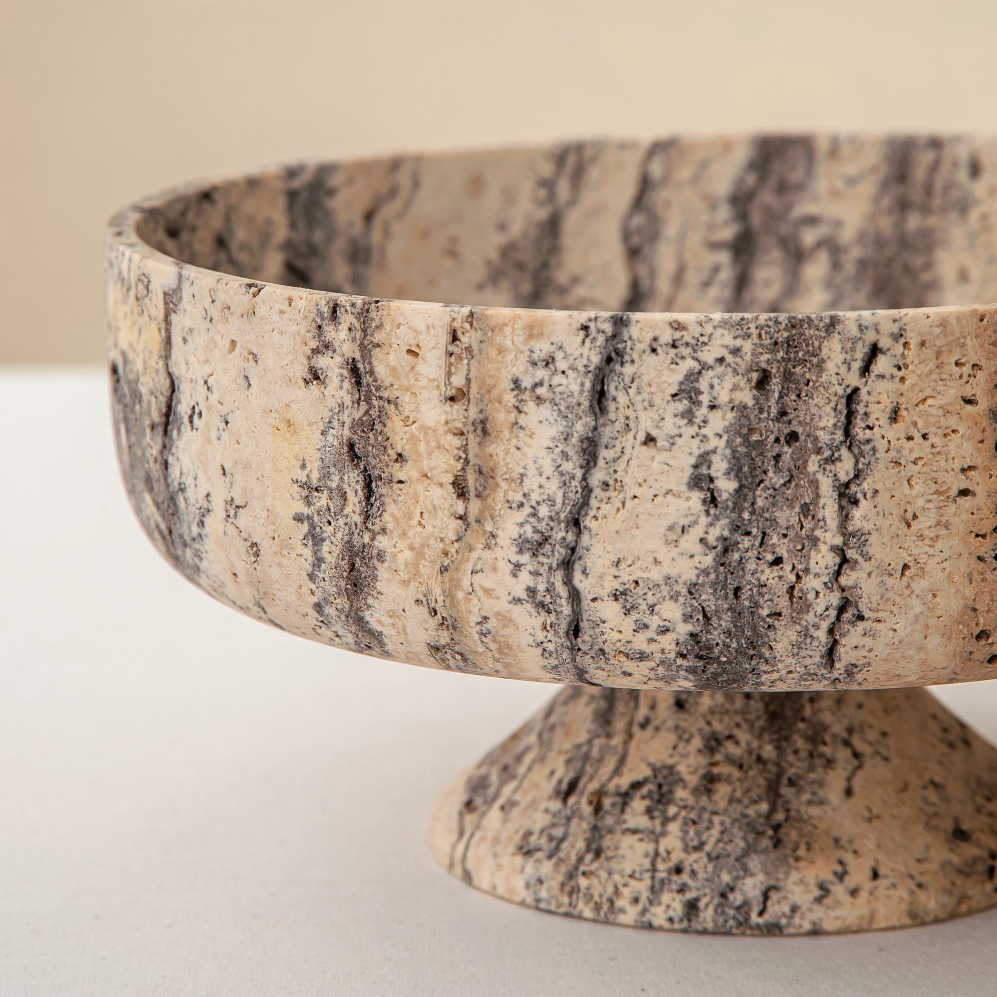 Handcrafted Gaia travertine bowl with wide shallow basin and pedestal base, featuring natural stone veining, by Uniiqo Studio
