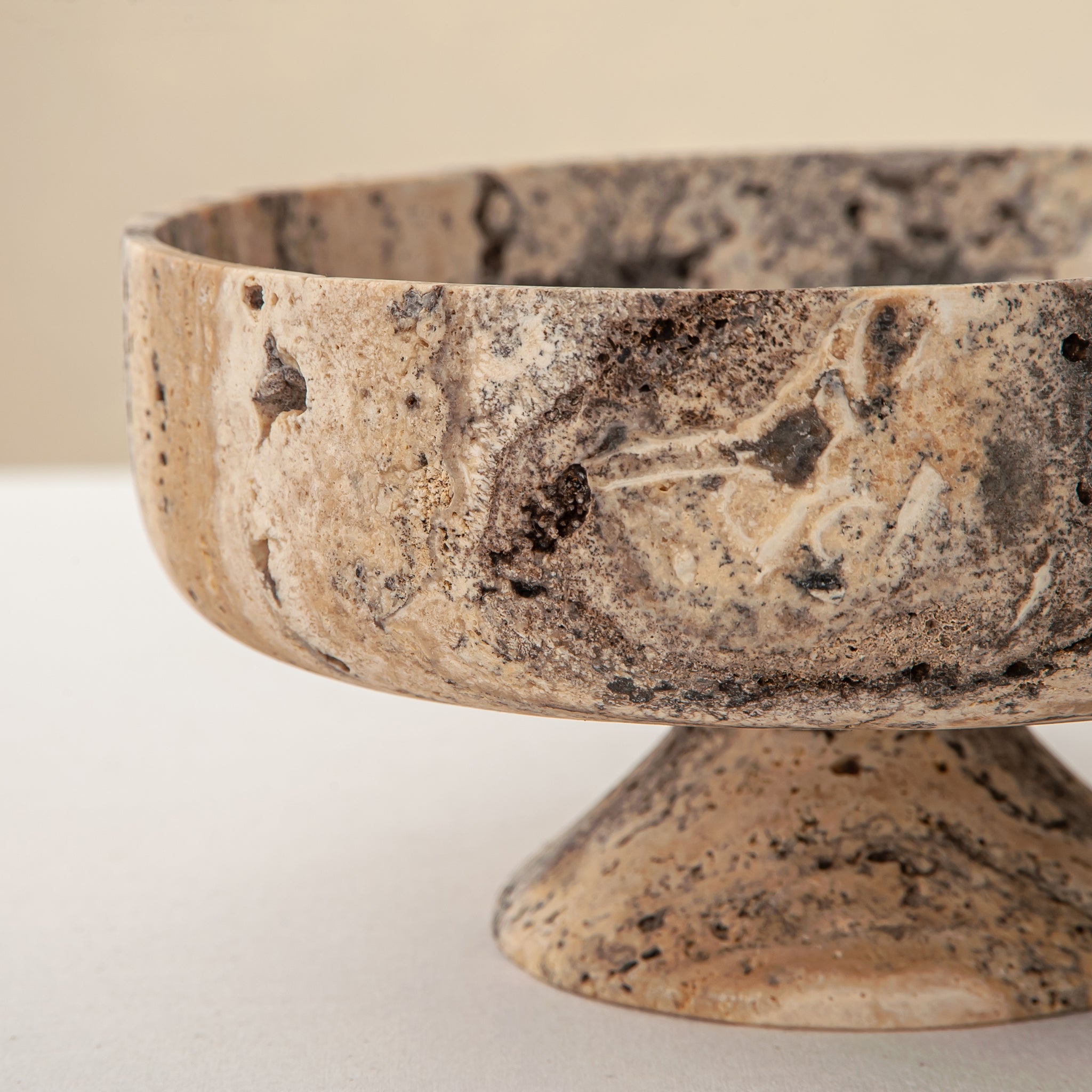 Handcrafted Gaia travertine bowl with wide shallow basin and pedestal base, featuring natural stone veining, by Uniiqo Studio