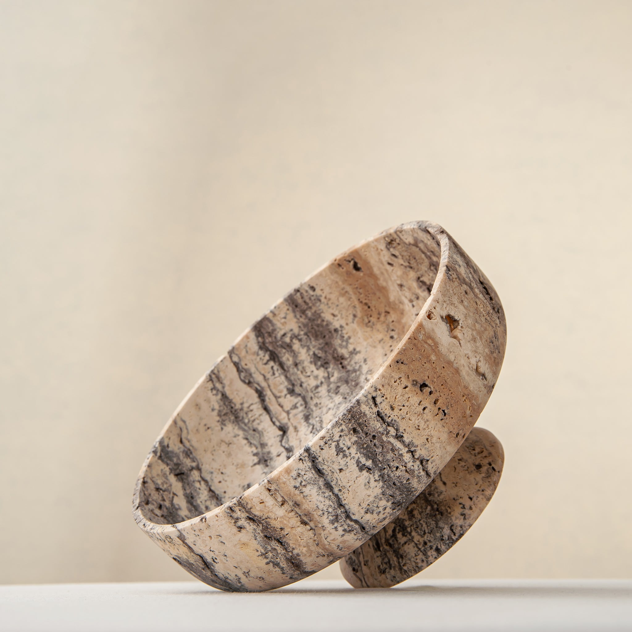Handcrafted Gaia travertine bowl with wide shallow basin and pedestal base, featuring natural stone veining, by Uniiqo Studio